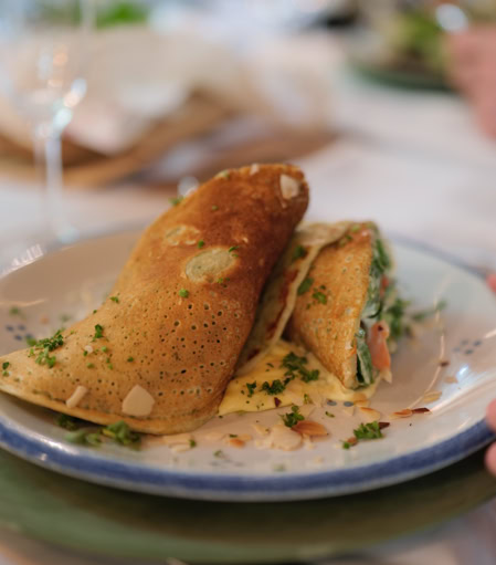 Zwei gefüllte Crêpes auf einem Teller, garniert mit Kräutern.